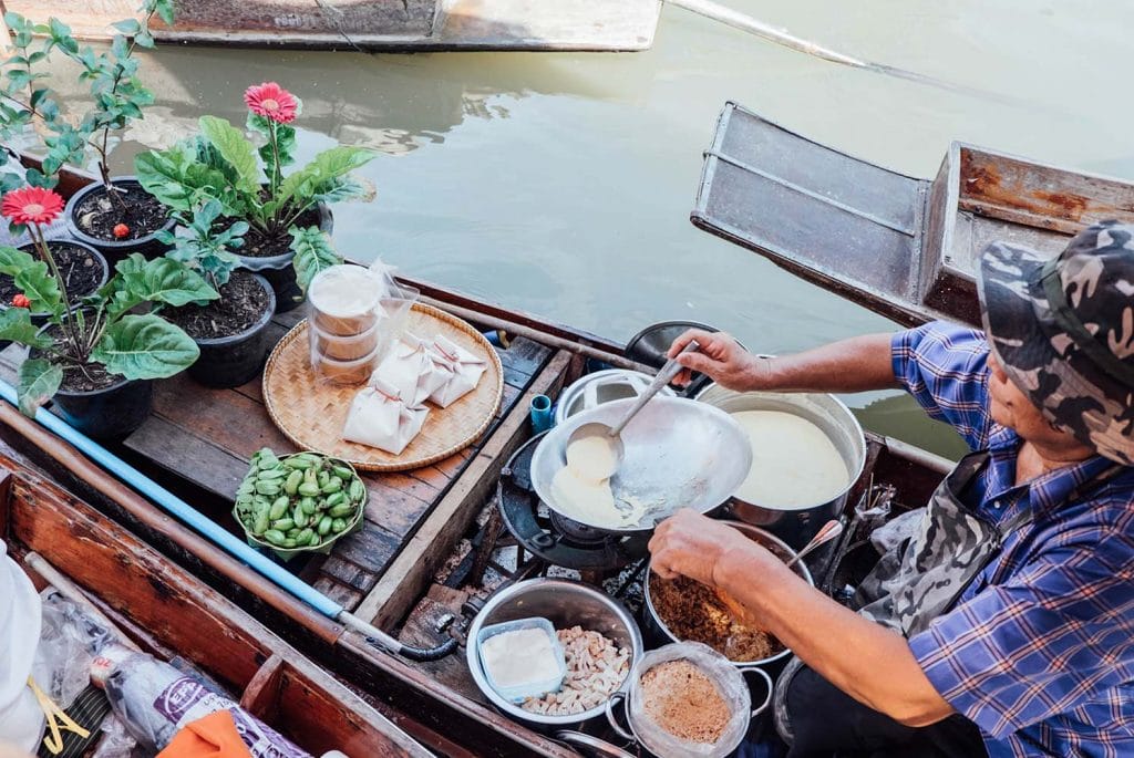Woman cooking Thai pancake in a small wooden boat