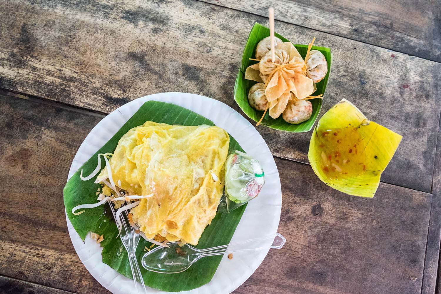 Thai breakfast with folded omelette and dumplings on a wooden table at a floating market in Bangkok