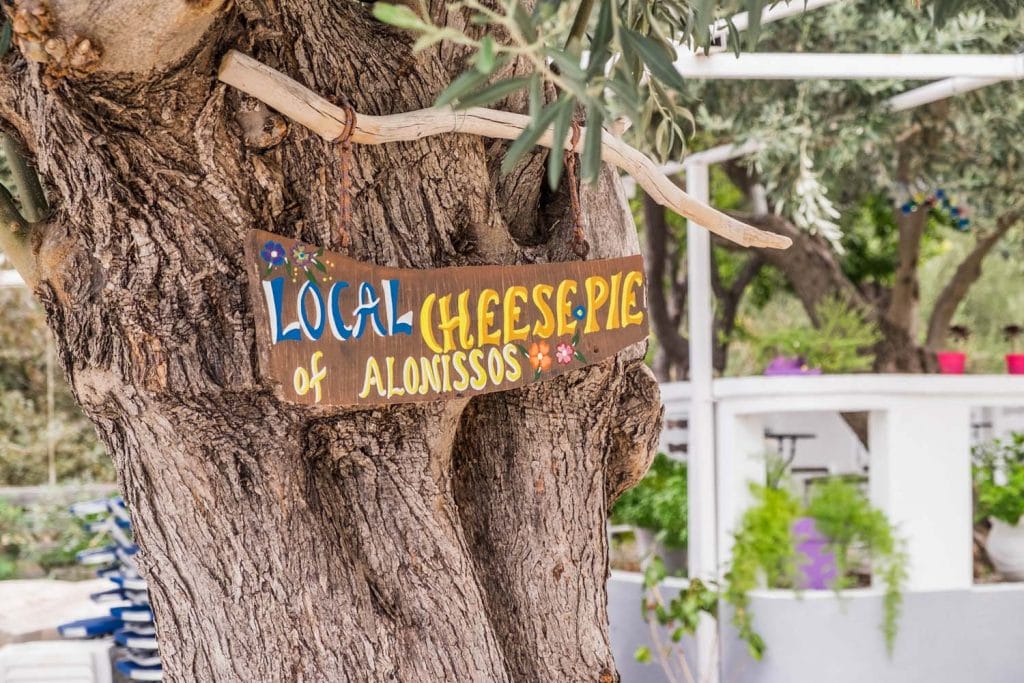 Tree with sign saying Local Cheese Pie of Alonissos