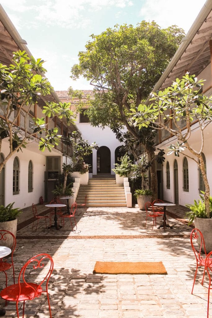 Courtyard with red chairs and stairs leading up to a door