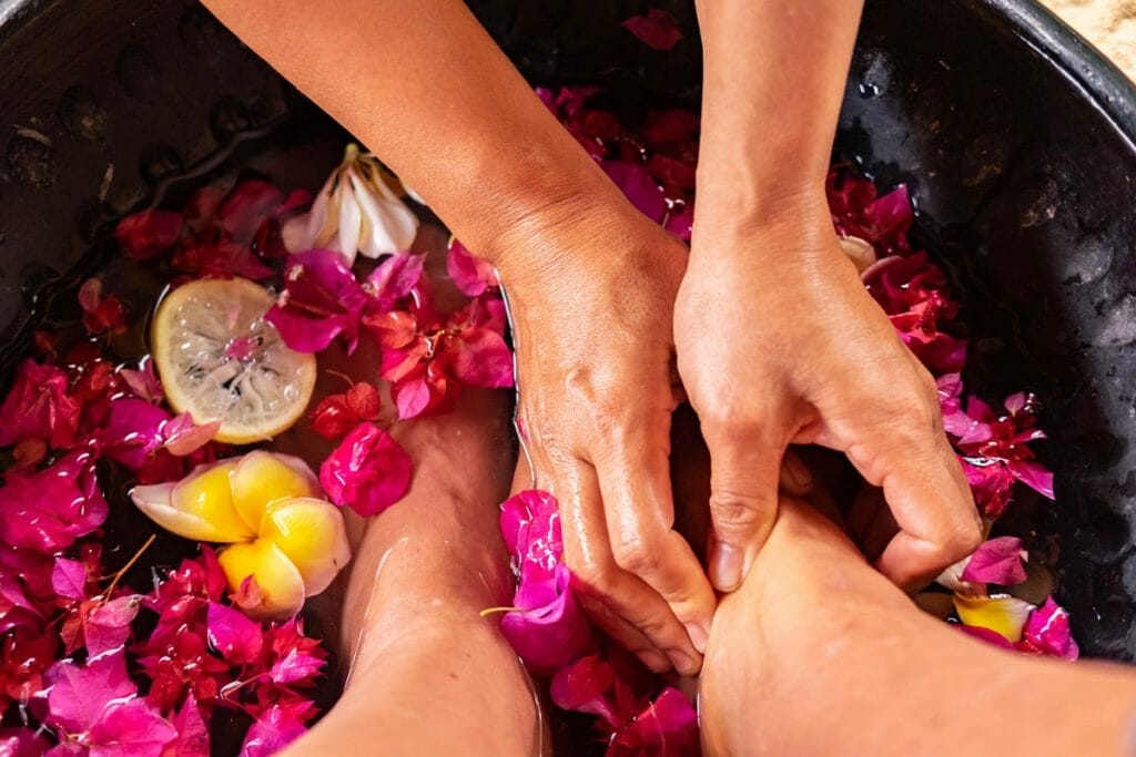 hands massaging a foot in flower bath
