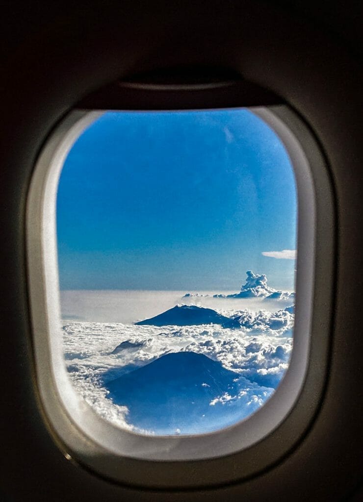Airplane window with view over two volcanos in the clouds in Indonesia