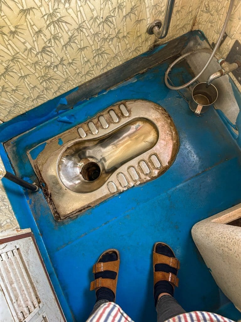 squat toilet on a blue floor in a train in india